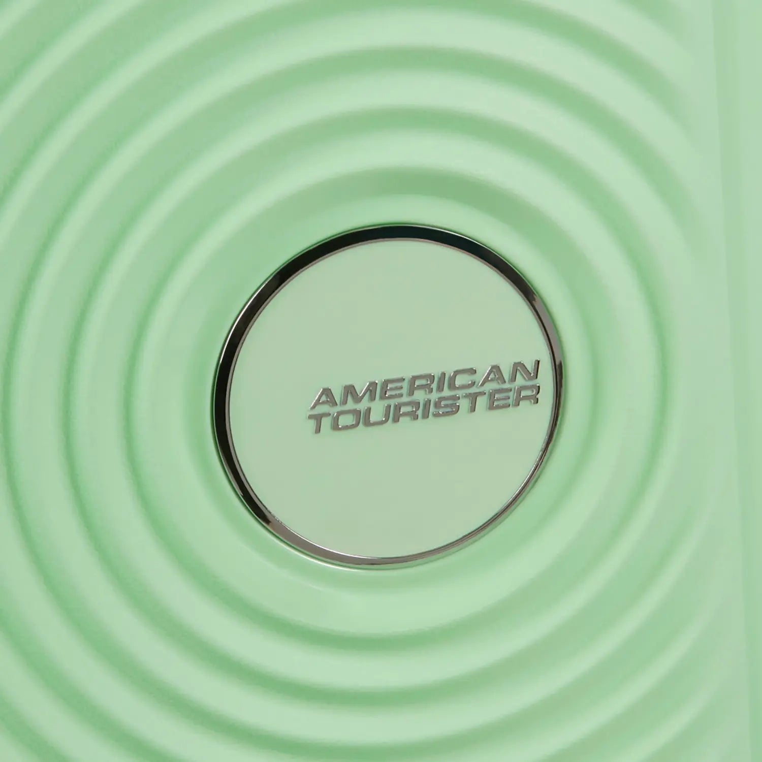 Silbernes American Tourister Logo auf hellgrünem Trolley mit markantem kreisförmigen Design