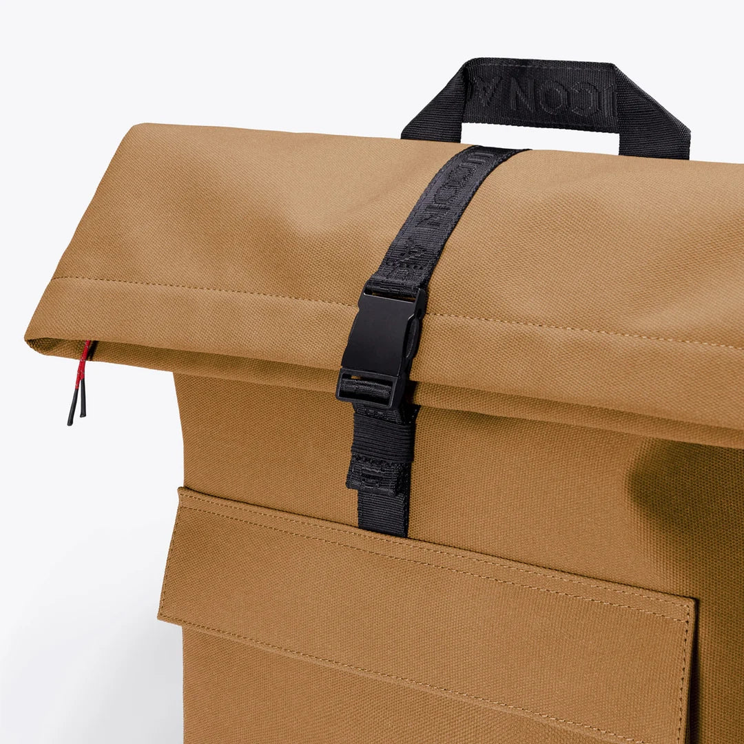 Detailansicht des Ucon Acrobatics Phantom Jannik Rucksacks – Dark Sand Reflect mit reflektierender Oberfläche und Rolltop-Schnallen-Verschluss